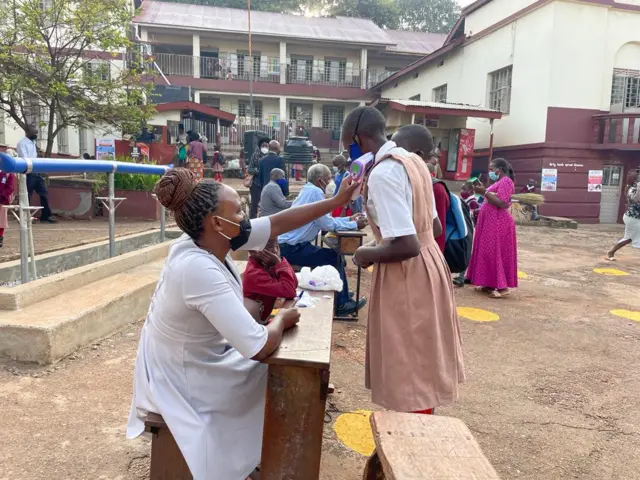 A pupil gets her temperature checked