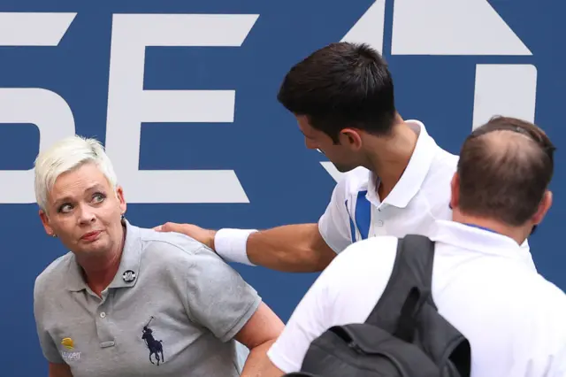 Novak Djokovic of Serbia tends to a line judge Laura Clark who was hit with the ball during his Men's Singles fourth round match.