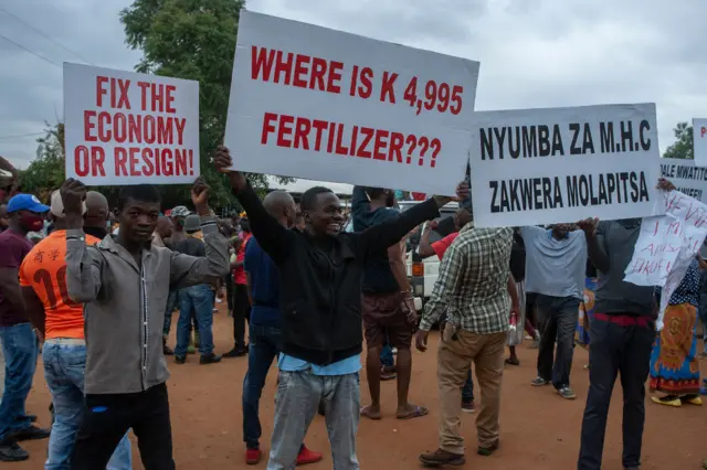 Demonstrators hold placards as they gather during a demonstration in Lilongwe on November 26, 2021.