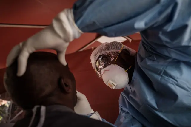 enyan doctor Legson Chesimet (R) performs a swab test on a patient to test for the COVID-19 coronavirus