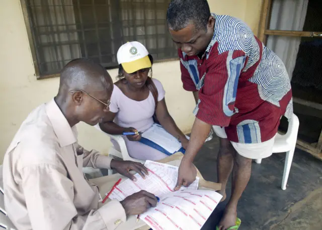 Anthony Odili (R) gives his finger print after census counters (C and L) made the headcount of his family 21 March 2006, in Asaba, Delta State.