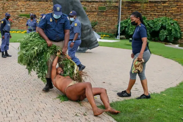 King Khoisan South Africa holds on to a marijuana plant as Tshwane Metro Police Department (TMPD) member drags him as they try to confiscate the plants during a raid at the Union Buildings in Pretoria on January 12, 2022