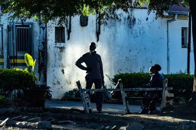 Purity Gowere (R) wife t detained freelance journalist Jeffery Moyo talks to a prison services officer outside Bulawayo Prison in Bulawayo on June 15, 2021.