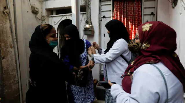 A healthcare worker administers a dose of a coronavirus disease (COVID-19) vaccine during a door-to-door vaccination campaign in a slum in Karachi, Pakistan,