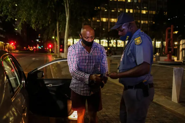 A South African police officer looks at the driver's licence of a motorist in 2020