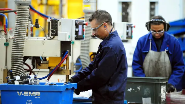 Skilled workers operating machinery at a manufacturing company