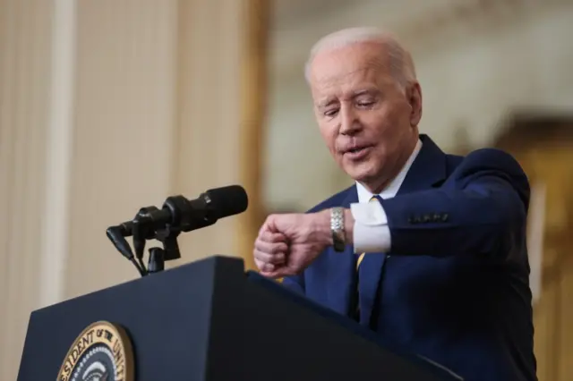 President Biden looks at watch during press conference