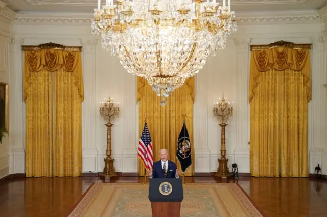 U.S. President Joe Biden holds a formal news conference in the East Room of the White House, with chandellier and grand setting visible