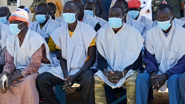 Released prisoners sit in the shade during a ceremony at the Klessoum prison in N'Djamena, Chad, on 18 January 2022