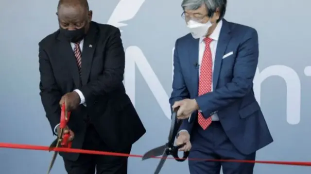 South African President Cyril Ramaphosa (L) and founder of NantWorks Dr Patrick Soon-Shiong (R) cut a ribbon using giant scissors  during the inauguration of the Nant-SA Vaccine Production Facility in Cape Town, South Africa, 19 January 2022