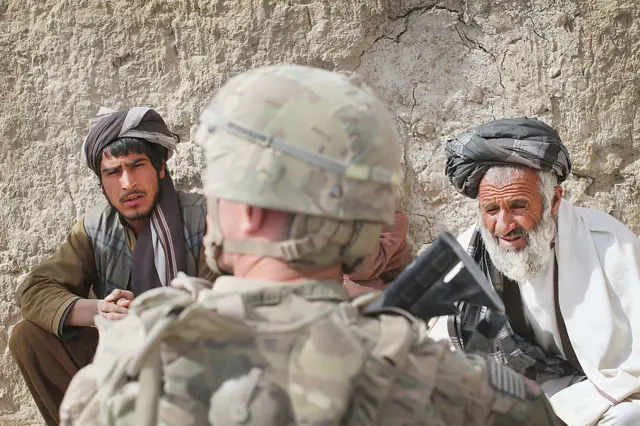 Wes Brockbank from Seattle, Washington with the U.S. Army's 4th squadron 2d Cavalry Regiment questions residents during a joint patrol through a village with soldiers from the Afghan National Army