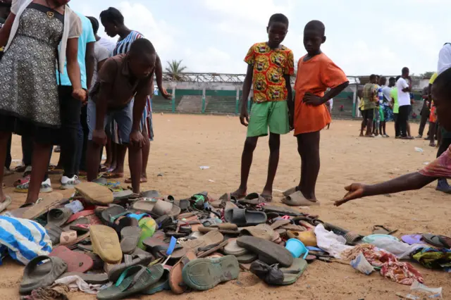 People search through piles of shoes left at a field in Monrovia, on January 20, 2022, where 2