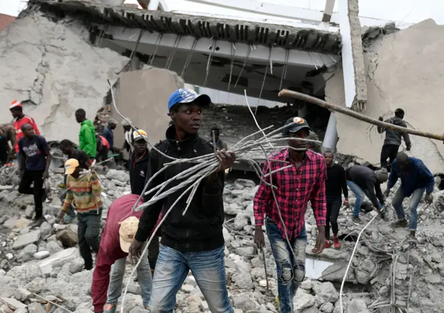 Scrap metal dealers carry used metal after heavy machinery demolished The South End Mall, in Nairobi on August 31, 2018