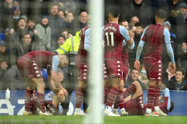 Former Everton player Lucas Digne holds his head on the floor after being hit by a bottle thrown from the crowd