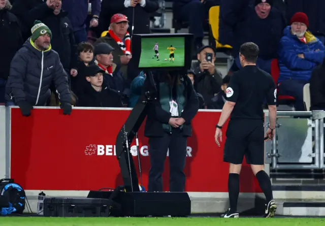 Referee Peter Bankes assesses VAR footage