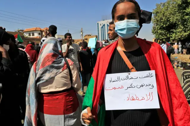 A Sudanese protester carries a placard which reads in Arabic "long live the struggle of women, they alone can break the silence of oppression"  in Khartoum on 24 January.