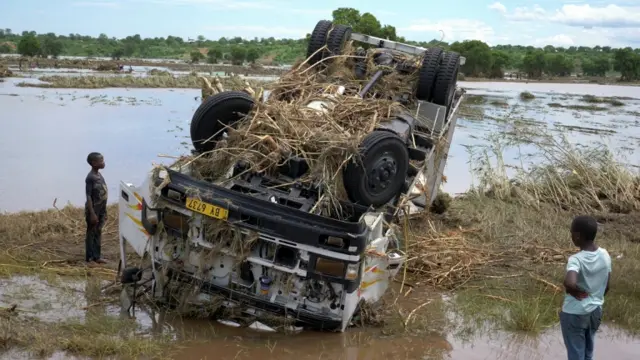 People look at a wreck washed away during tropical storm Ana on the flooded Shire river, an outlet of Lake Malawi at Thabwa village, in Chikwawa district, southern Malawi, 26 January.