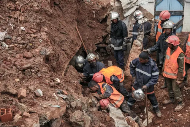 Firefighters search through rubble after a car park housing several private cars collapsed on houses following the heavy rains of the last few days in the Ankadifotsy neighbourhood of Antananarivo on 24 January.