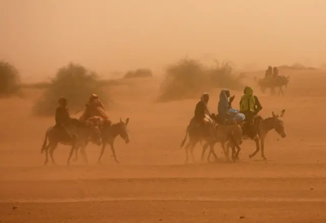 Internally displaced girls ride donkeys during a sandstorm outside ZamZam IDP"s camp in Al Fasher