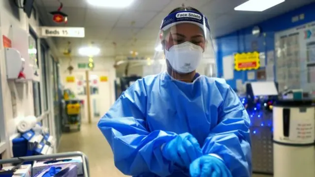 A nurse puts on full PPE on a ward for Covid patients at King's College Hospital, on 21 December 2021