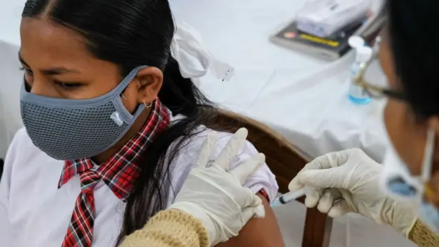 A healthcare worker administers a dose of Covaxin vaccine to a student at Barasat Girls High School, India