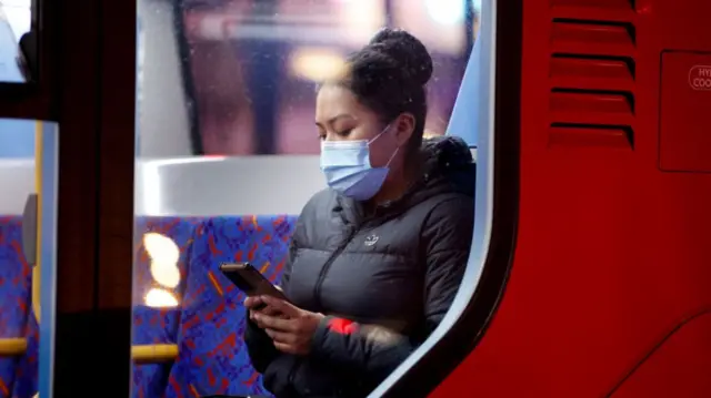 A woman on a bus in a face mask