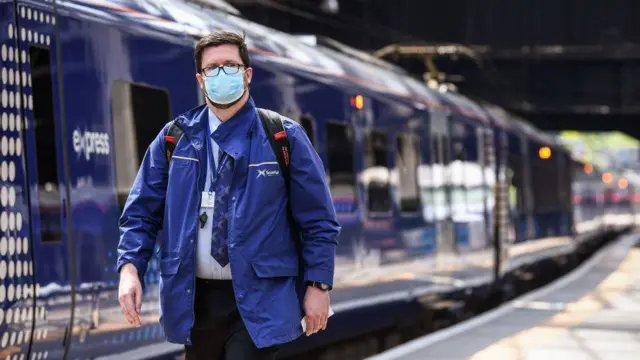 A member of ScotRail staff walks alongside a train