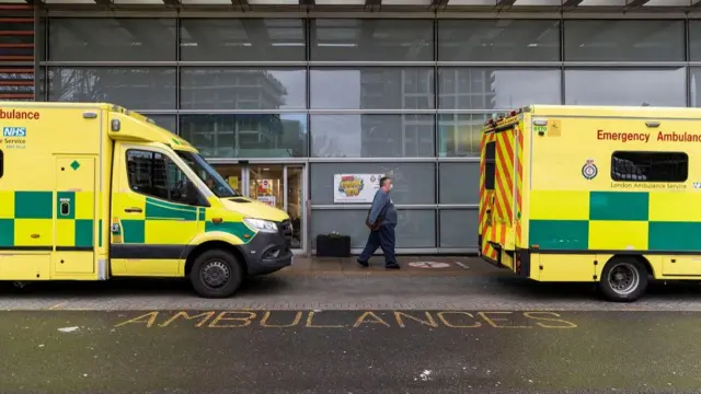 A man wearing a face mask, amid the spread of the coronavirus disease (COVID-19), walks past the ambulances at the Royal London Hospital, in London, Britain December 31