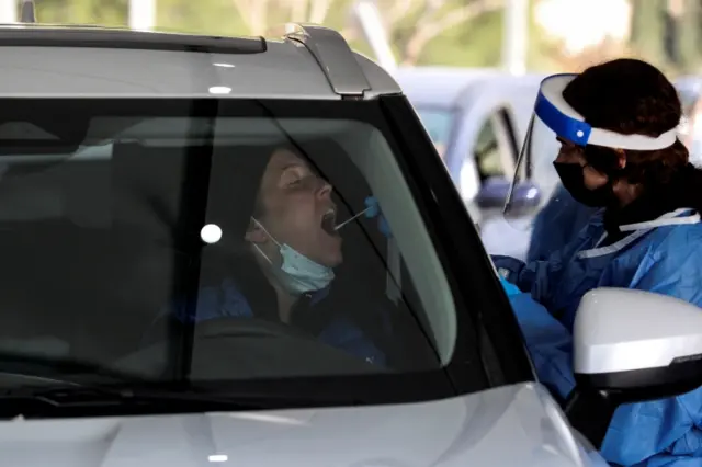 A woman is tested for the coronavirus disease at a drive-through site as Israel faces a surge in Omicron variant infections in Jerusalem on 3 January 2022