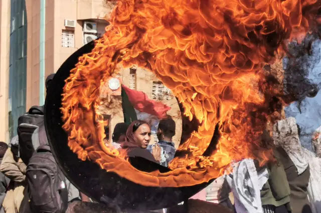 Woman standing near a burning tyre.