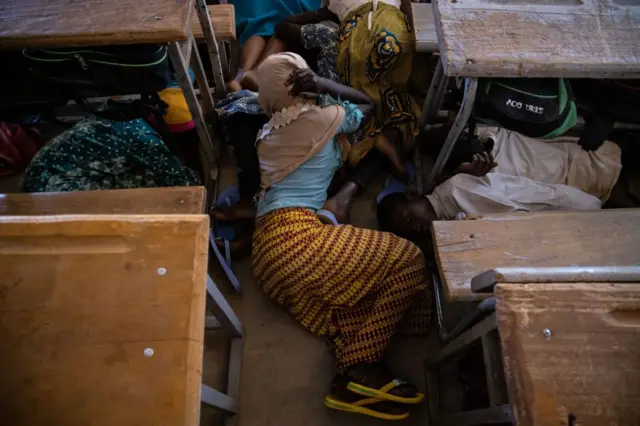 A primary school girl lies on the floor of her classroom during an emergency attack simulation in Dori on February 3, 2020.