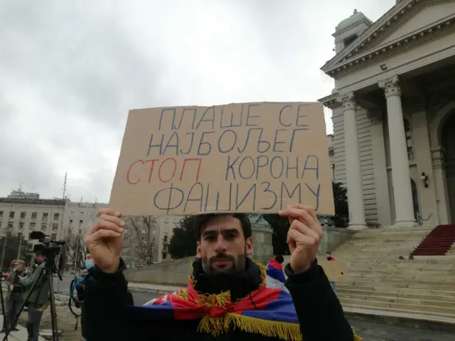 Novak Djokovic supporter carrying sign reading "They are afraid of the best one. Stop Corona fascism"