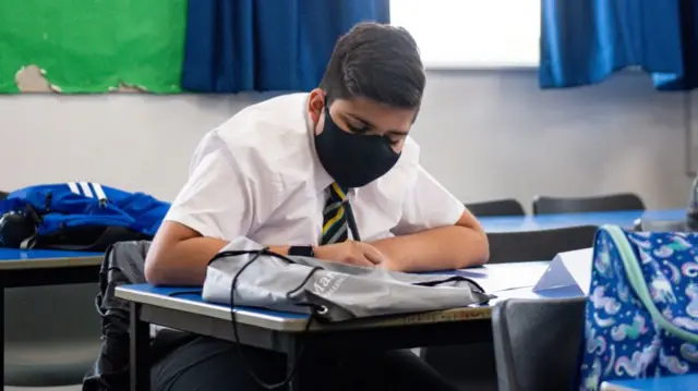 Boy in classroom wearing mask and working