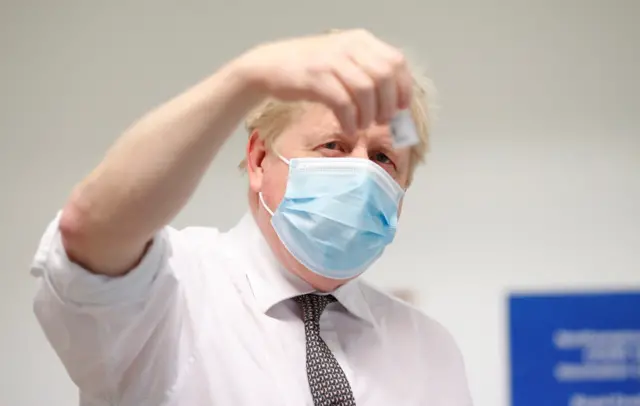 Prime Minister Boris Johnson checks a coronavirusvaccine during a visit to a vaccine centre in Northampton