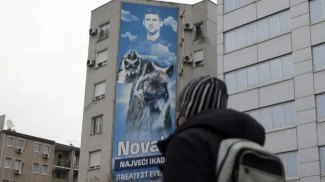 A man walks past a huge billboard depicting Serbian tennis player Novak Djokovic in Belgrade, Serbia, 06 January 2022