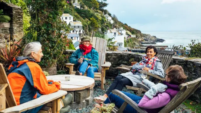 Four ladies meeting up outside and sitting socially distanced