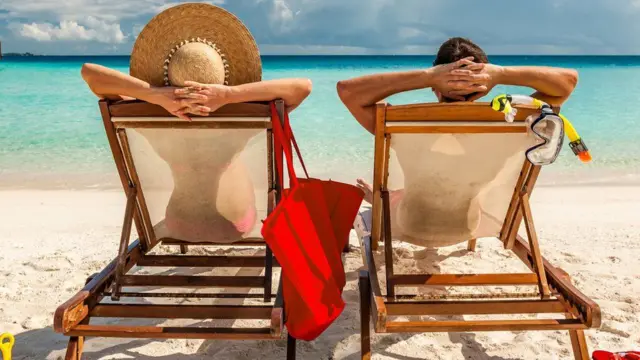 People on deck chairs on the beach