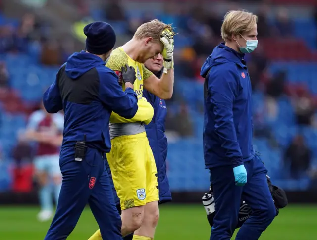 Huddersfield  goalkeeper Ryan Schofield is led off the field after being injured