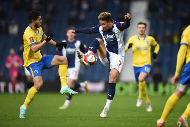 West Bromwich Albion's English striker Callum Robinson (C) controls the ball in front of Brighton's English midfielder Steven Alzate