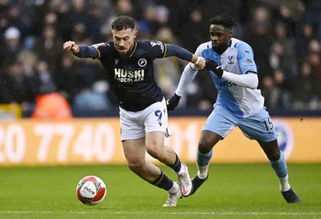 Millwall's Tom Bradshaw in action with Crystal Palace's Jeffrey Schlupp