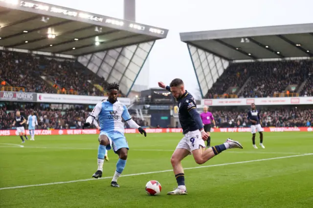 Jeffrey Schlupp of Crystal Palace attempts to block Tom Bradshaw of Millwall