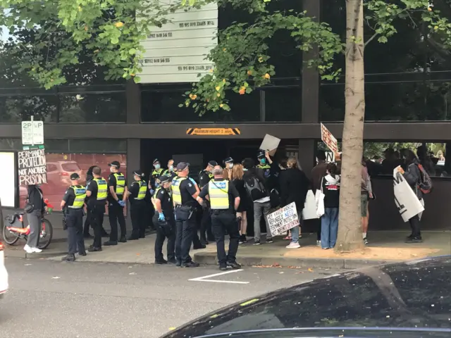 Police and protesters outside the Park Hotel earlier today