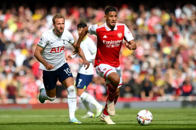 William Saliba of Arsenal runs with the ball whilst under pressure from Harry Kane of Tottenham Hotspur