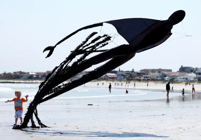 A boy plays with a kite depicting a dementor from the Harry Potter series during the 28th Cape Town International Kite Festival, an awareness-campaign for World Mental Health Day where kite enthusiasts gather to fly colourful kites, participate in social activities, and raise funds for mental health support at Melkbosstrand, Cape Town, South Africa, October 9, 2022