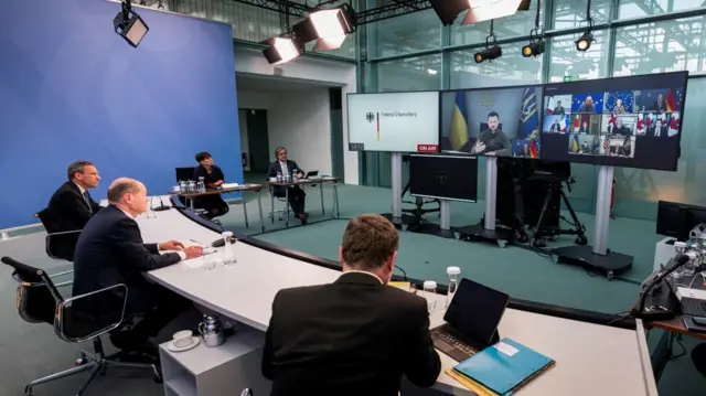 Ukrainian President Volodymyr Zelenskiy appears on a screen as German Chancellor Olaf Scholz attends a virtual G7 leaders meeting at the Chancellery in Berlin, Germany, October 11, 2022.