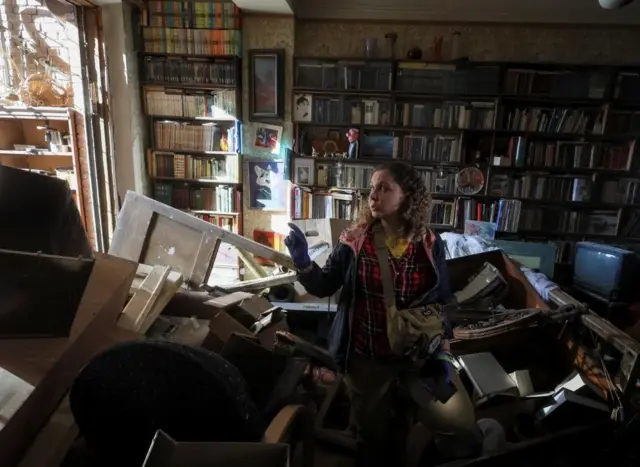 A woman stands inside her flat on Tuesday in central Kyiv, after it was hit by missile strikes on Monday