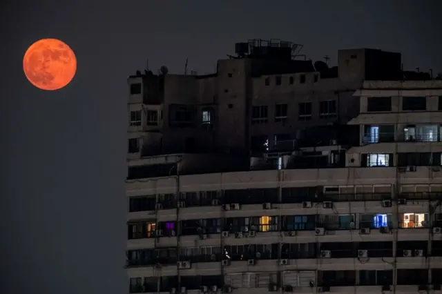 The waning gibbous moon rises behind a high-rise residential building in the central island of Manial in Egypt's capital Cairo on 10 October.