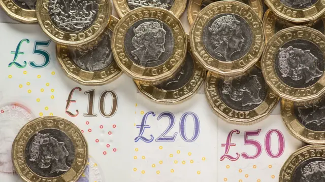 A UK five pound, ten pound, twenty pound and fifty pound notes with one pound coins