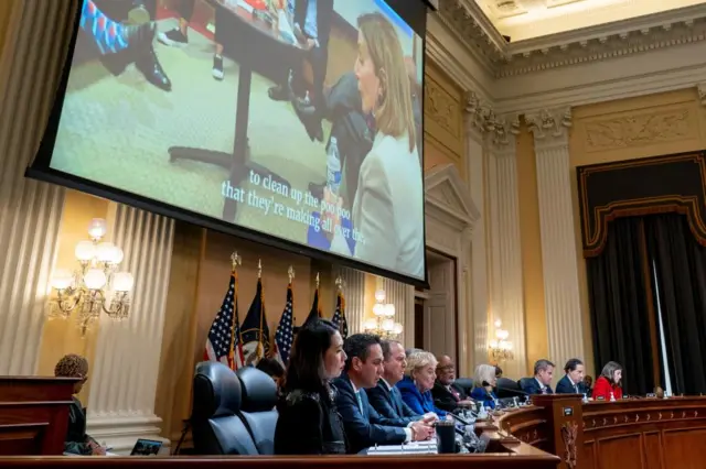 Nancy Pelosi seen on a big screen at the hearing