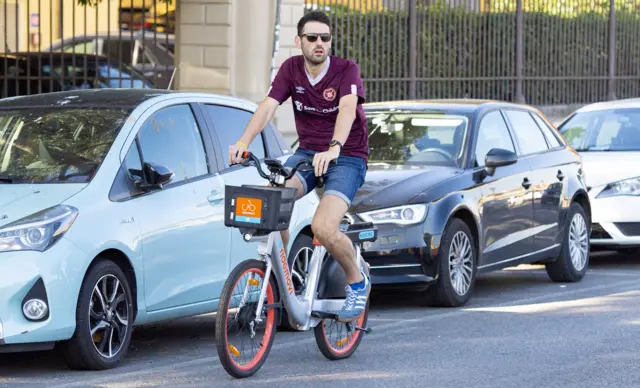 A Hearts fan cycling down the street in Florence